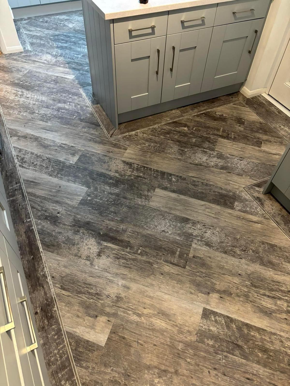 FloorsFitted.com showing off their luxury vinyl tile fitting expertise. In this kitchen is installed Amtico, with borders around the edges of the installation.